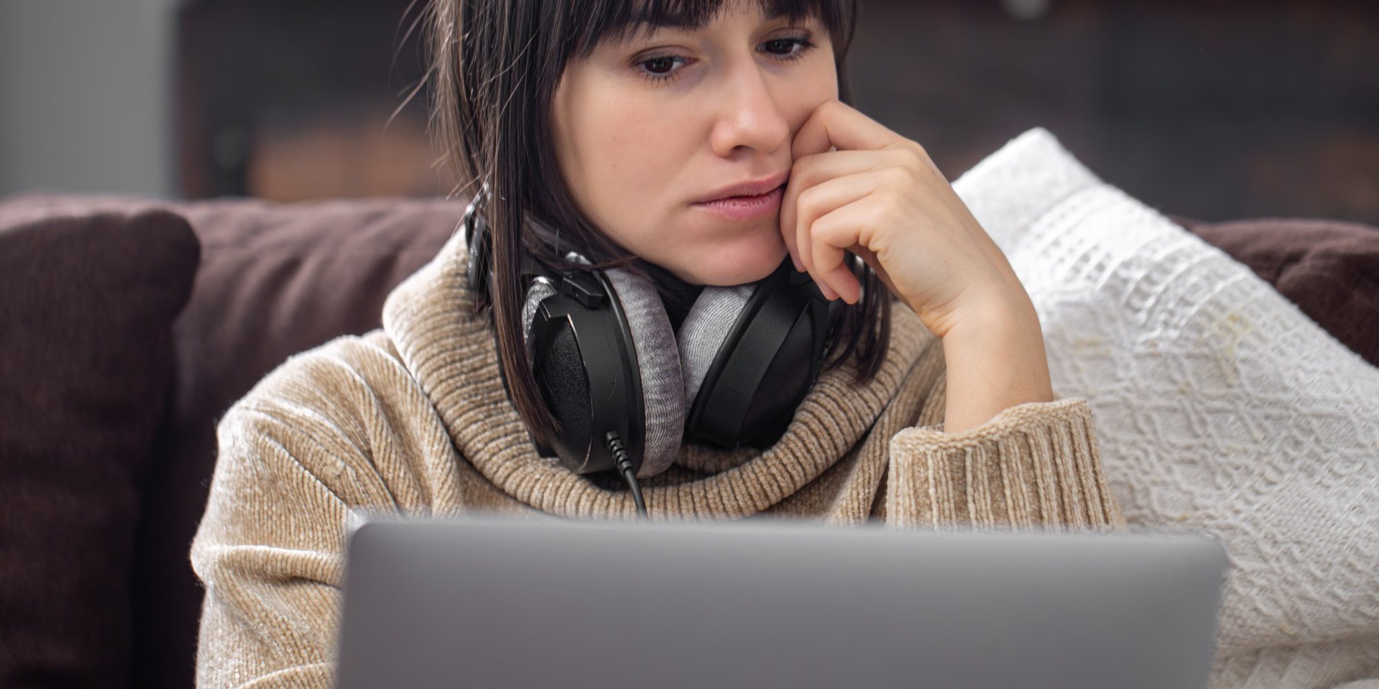 young-beautiful-brunette-headphones-cozy-sweater-looks-laptop-screen